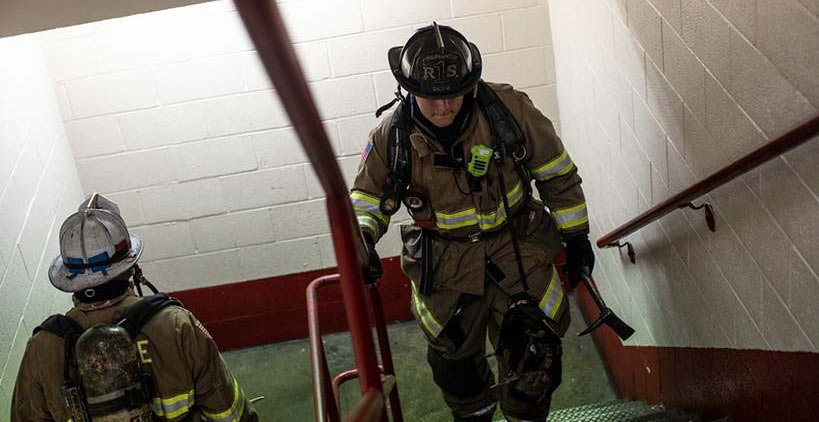 Firefighters climbing stairs inside a building